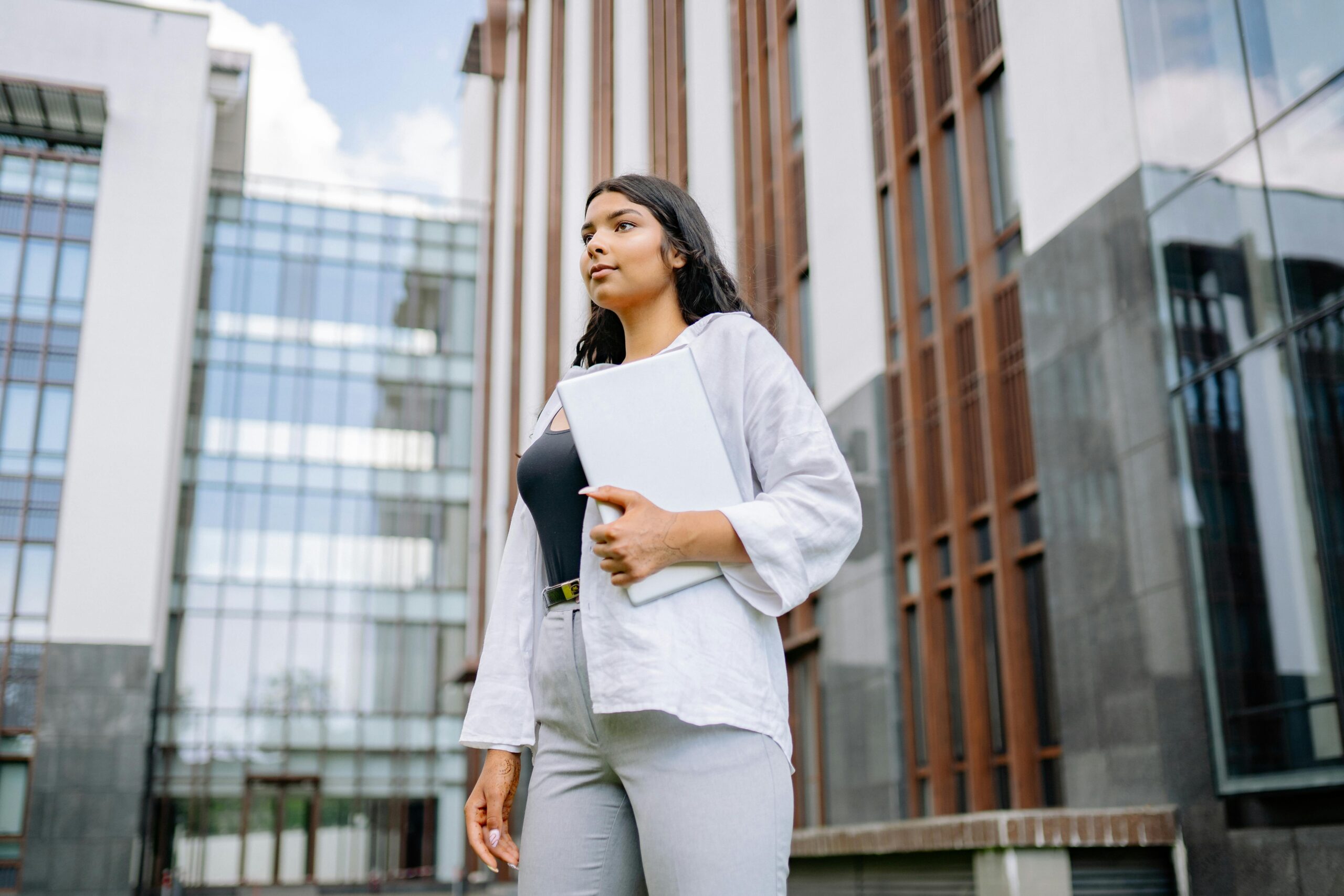 Photo by Yan Krukau: https://www.pexels.com/photo/woman-holding-a-laptop-near-building-8837155/